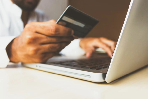 A person holding a credit card in one hand while buying THCA flower online