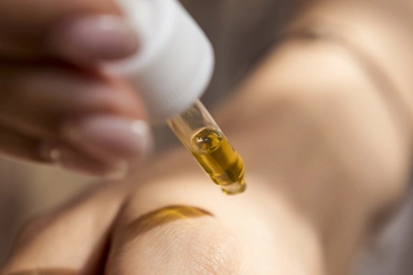 Close-up of a hand using a dropper to apply a HHC tincture