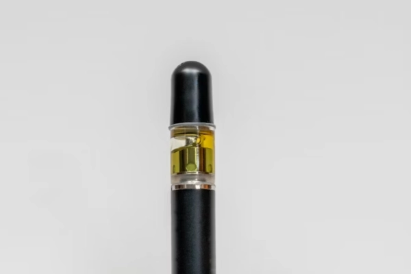 Close-up of a vape cartridge filled with cannabis concentrate, featuring a sleek black mouthpiece