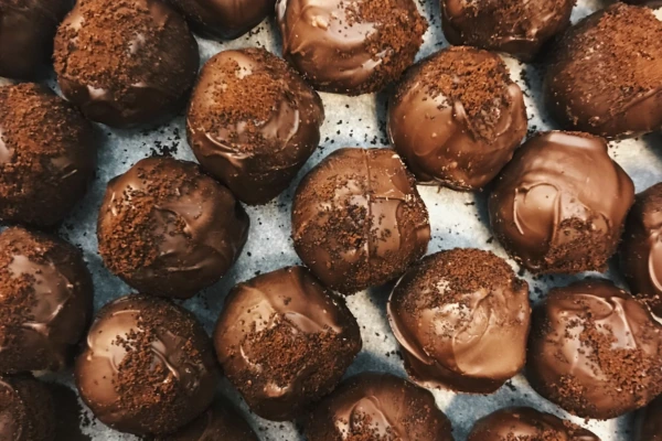 Tray of rich, dark chocolate truffles with a textured topping, arranged in rows