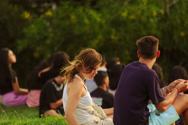 A group of people sitting on the grass, enjoying an outdoor setting